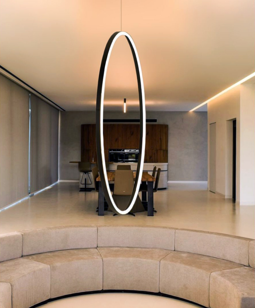 A vertical LED ring chandelier hangs from an adjustable aircraft cable suspension kit, making an elegant centerpiece in the modern living room.