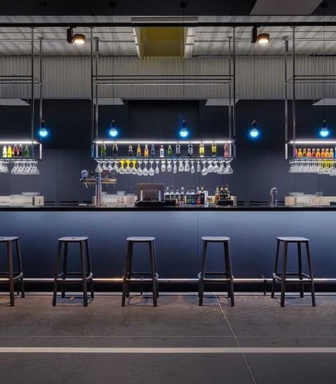 Blue RGB LED bulb pendant lights create ambience over a bar with white track lights for general lighting.