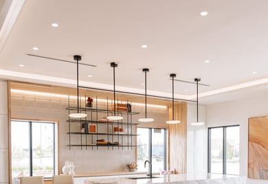 Trimless recessed downlights provide ambient light from a vaulted ceiling in an office kitchen while an LED pendant over the kitchen island for task lighting