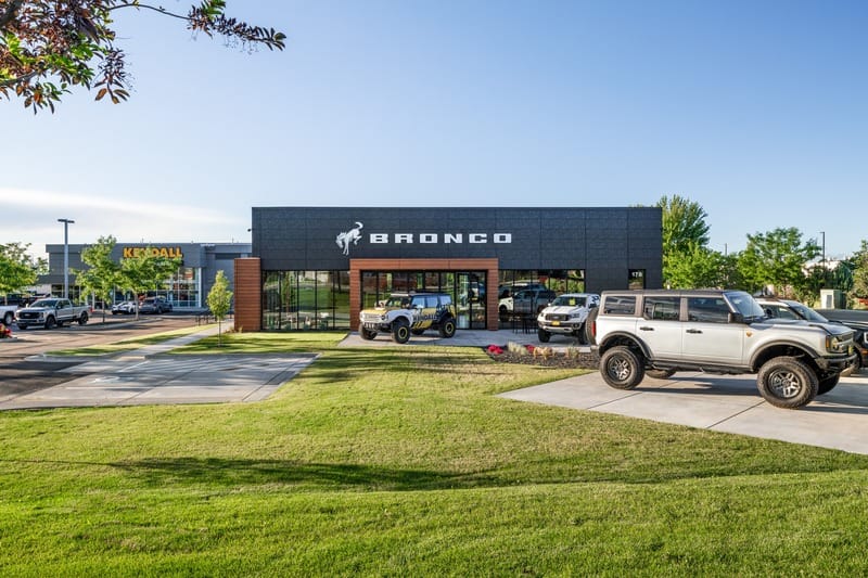 An exterior shot of the Kendall Bronco car dealership, showing parking lot lights.