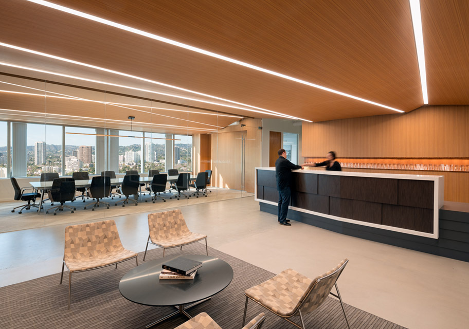 Linear recessed lights set in a zig-zag pattern illuminate an office reception desk