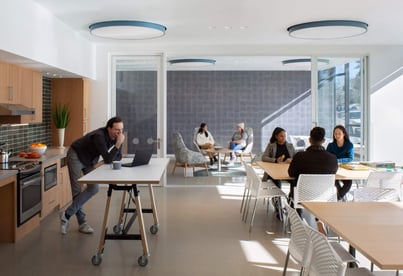 Round recessed LED lights provide general lighting over a gathering space and task lighting over a kitchen counter.