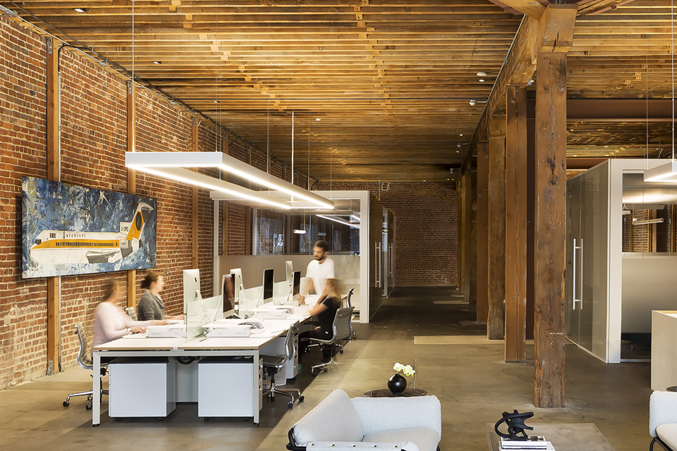 A rectangular LED pendant light hangs over an office workspace