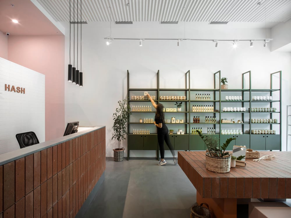 Black cylinder pendant downlights provide task lighting over the checkout counter at a Hash retail store.