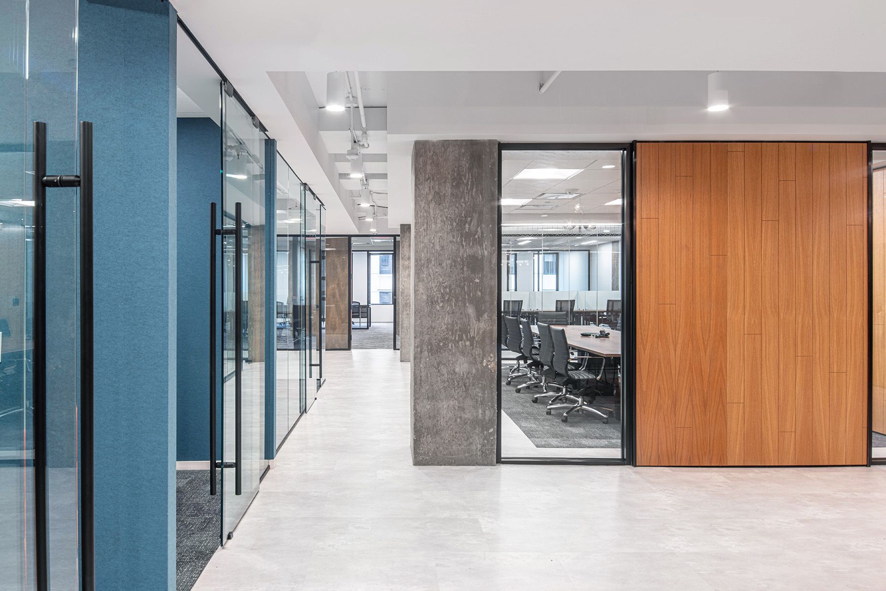 White cylinder downlights suspended from an exposed ceiling light the hallway of a speculative suite office.