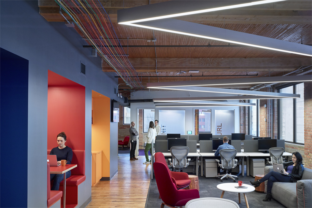 Linear pendant lighting shown with angled connectors to make a seamless zig-zag pattern in the common area of this contemporary office design.