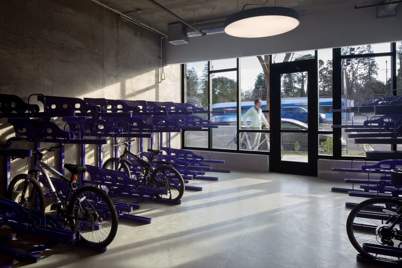 Round disk lights with daylight sensors increase illumination as the day fades in an apartment bike room facing the street.