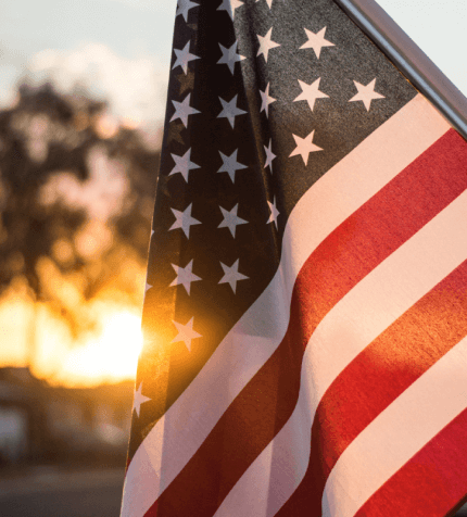 An American flag hangs in the setting sun.